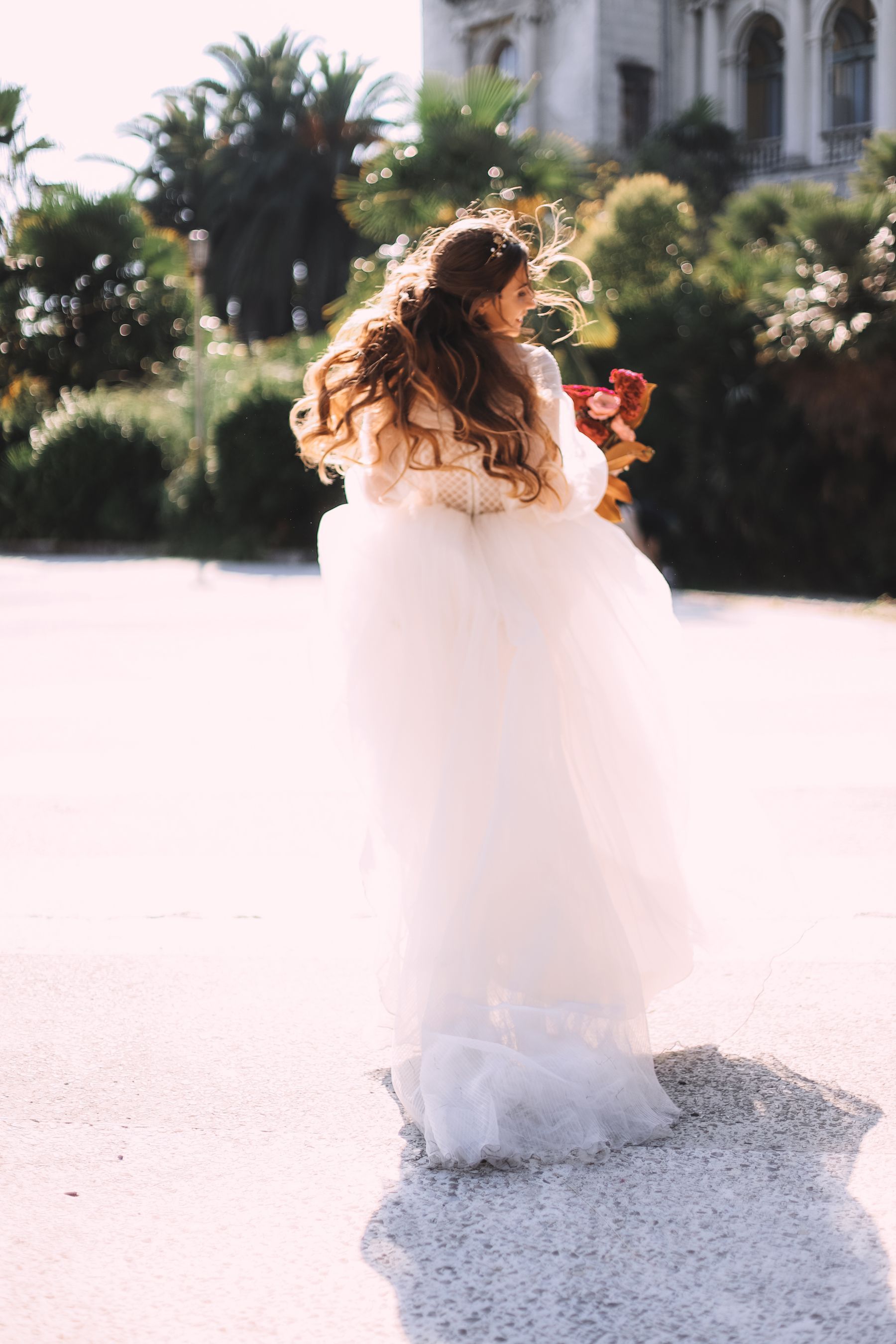 Vestido de novia blanco y vaporoso, visto de espaldas en un jardín